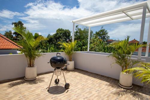 a grill on a balcony with palm trees at Sunterra - Brand new villa - Ricefield View, Canggu - Rooftop in Kerobokan
