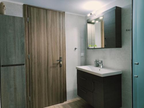 uma casa de banho com um lavatório e uma porta de madeira em Lucy's luxury II em Néa Koútali