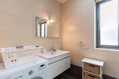 La salle de bains blanche est pourvue d'un lavabo et d'un miroir. dans l'établissement St Julians apartment-Hosted by Sweetstay, à San Ġiljan