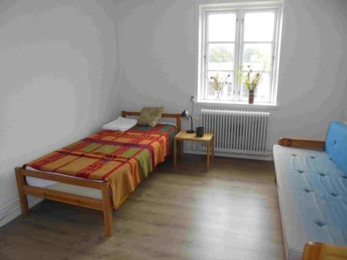 um pequeno quarto com uma cama e uma janela em Christianslund em Randers