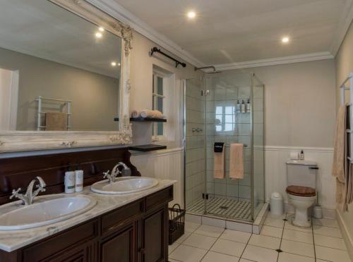 a bathroom with two sinks and a glass shower at Old Rearsby in Mooirivier