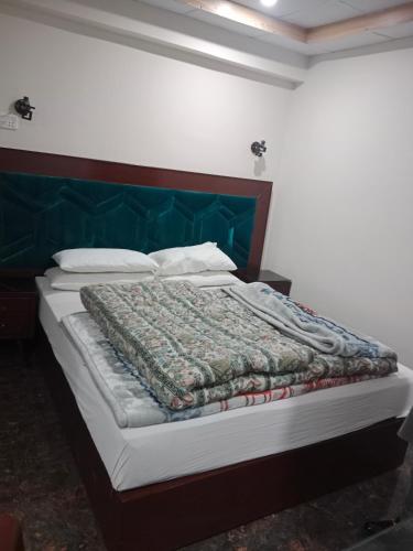 a bedroom with a bed with a green headboard at AL KHALEEJ HOTEL in Murree