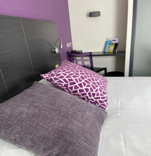ein Bett mit einem lila und weißen Kissen darauf in der Unterkunft Kyriad Direct Limoges Nord in Limoges