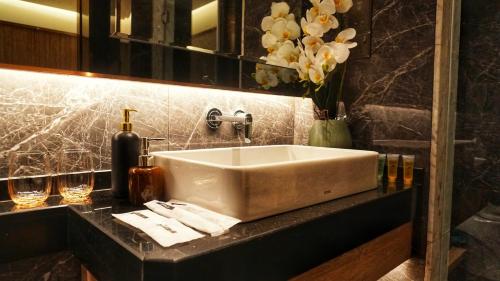 a bathroom with a sink and flowers on a counter at Imperial Luxury Suites KLCC by Moonway in Kuala Lumpur