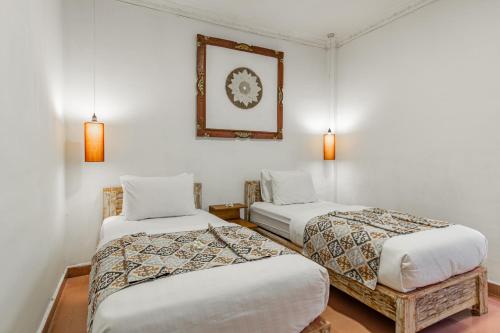 Habitación con 2 camas y una foto en la pared. en Capital O 93944 Geweka Homestay, en Jimbaran
