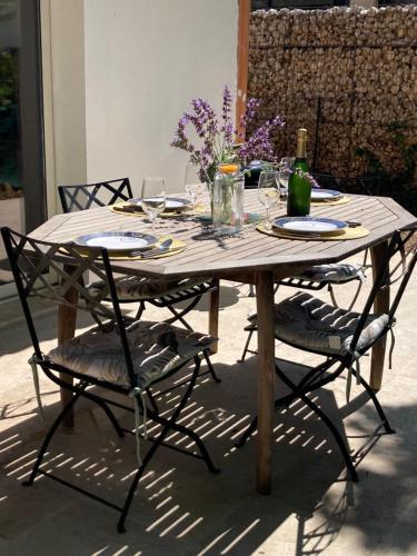- une table en bois avec 2 chaises et une bouteille de vin dans l'établissement Guest house Maison d'invités, à Le Rouret