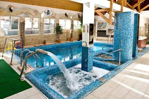 a swimming pool with a fountain in the middle at Kastélyszálló Wellness Resort Sóstó in Igricetanya
