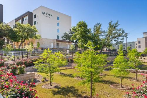 a garden with trees and flowers in front of a building at EVEN Hotel Austin Uptown near the Domain by IHG in Austin