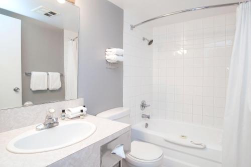 La salle de bains blanche est pourvue d'un lavabo et de toilettes. dans l'établissement Sandman Inn Cache Creek, à Cache Creek