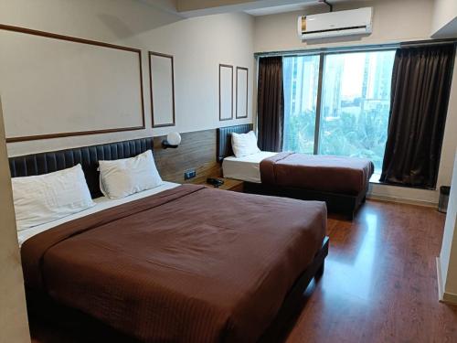 a hotel room with two beds and a large window at Crescent Rooms And Banquet in Surat