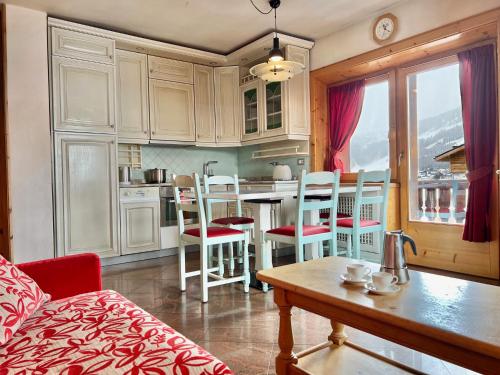 uma cozinha com armários brancos e uma mesa e cadeiras em Bike&Ski Saroch Apartments em Livigno