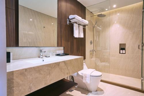 a bathroom with a toilet and a sink and a shower at Grand Palma Pangandaran by Horison in Pangandaran