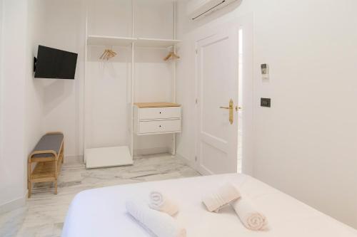a white bedroom with a bed and a tv at Granadi Apartamentos in Granada