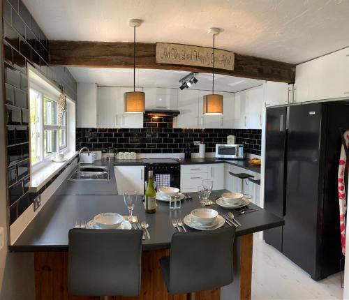 a kitchen with a table with chairs and a black refrigerator at The Lodge@Tyddyn Ucha in Caernarfon