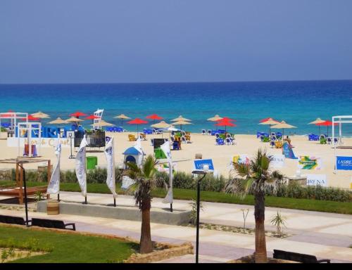 a beach with chairs and umbrellas and the ocean at Lasirena north coast Chalet With Roof , 3 rooms in Zāwiyat ‘Abd al Mun‘im