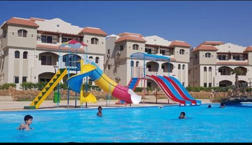 a swimming pool with slides and people in the water at Lasirena north coast Chalet With Roof , 3 rooms in Zāwiyat ‘Abd al Mun‘im