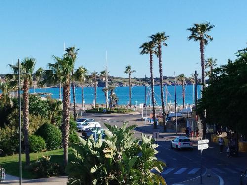 Una vista de una calle con palmeras y el océano. en Sanary Port et Plages Climatisé, en Six-Fours-les-Plages