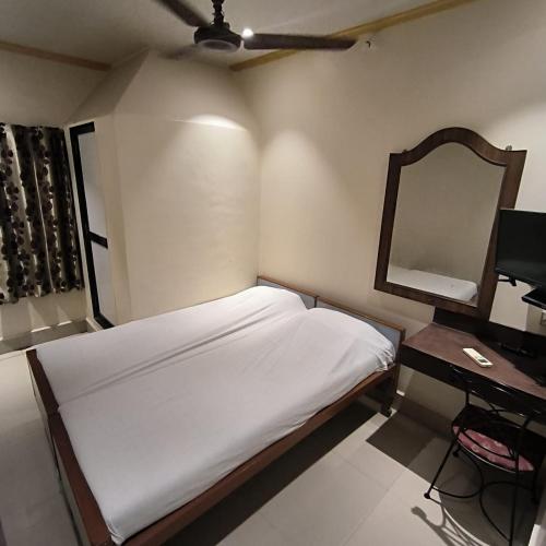 a small bedroom with a bed and a mirror at Hotel Rupali in Mumbai