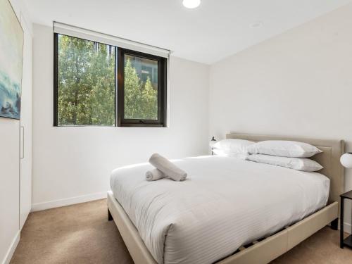 ein weißes Schlafzimmer mit einem großen Bett mit weißen Kissen in der Unterkunft Light Filled Apartment by Albert Park & Lake in Melbourne