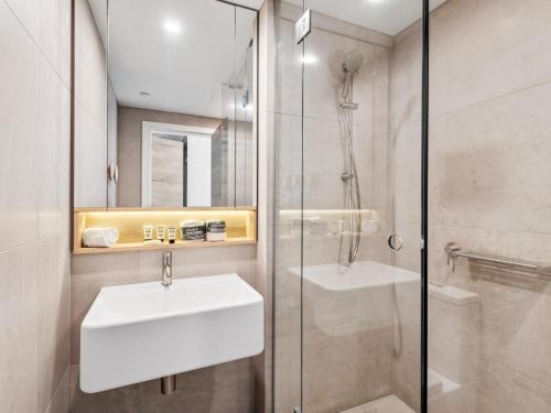 a bathroom with a white sink and a shower at Light Filled Apartment by Albert Park & Lake in Melbourne