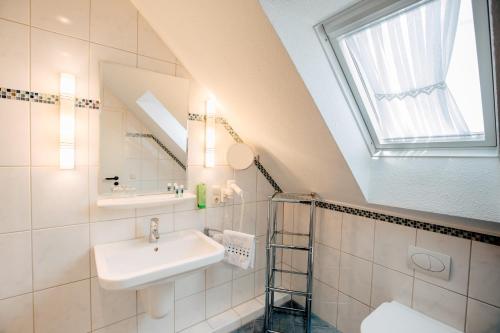 ein Bad mit einem Waschbecken und einem Spiegel in der Unterkunft Hotel Schiffer in Bensersiel