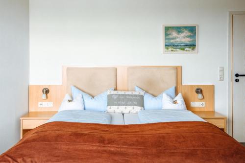 a bedroom with a large bed with a orange blanket at Hotel Schiffer in Bensersiel