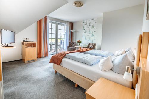 a bedroom with a large bed and a tv at Hotel Schiffer in Bensersiel