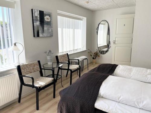 a bedroom with a bed and chairs and a table at Biersted Kro in Åbybro