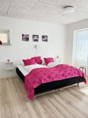 a bedroom with a large bed with a pink blanket at Biersted Kro in Åbybro