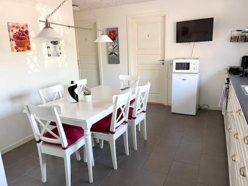 a kitchen with a white table and white chairs at Biersted Kro in Åbybro