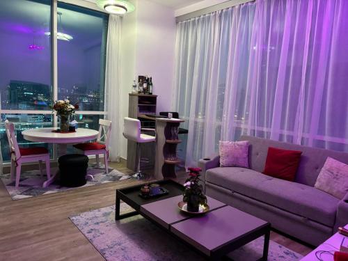 ein Wohnzimmer mit einem lila Sofa und einem Tisch in der Unterkunft Apartment in Al Sufouh 1st - Comfortable Home with 5 iconic views in Dubai