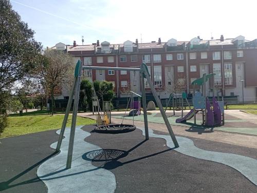 einen Spielplatz in einem Park mit einem Gebäude im Hintergrund in der Unterkunft Las MARIPOSAS , 3 habitaciones in El Astillero