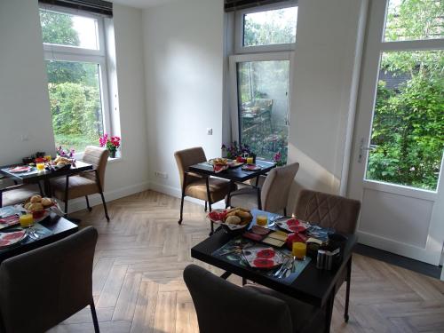 a dining room with tables and chairs and windows at B & B De Elsterberg in Elst