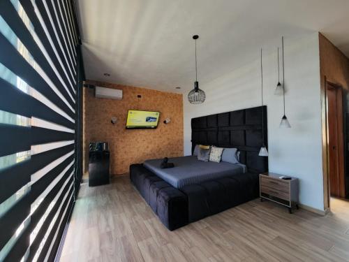 a bedroom with a black bed and a wall at Suite en Tlaquepaque centro in Guadalajara