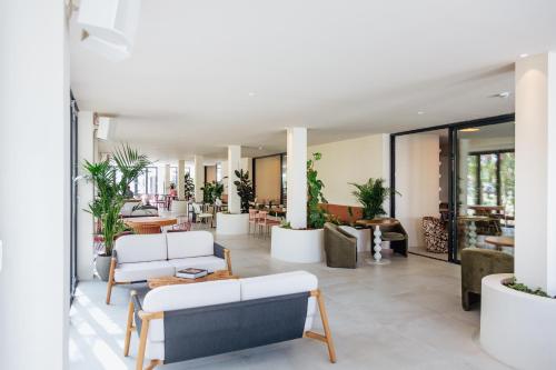 伊維薩城的住宿－El Hotel Pacha，客厅配有白色家具和植物