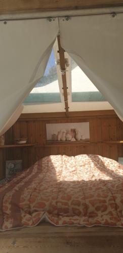 Bett in einem Zimmer mit einem großen Fenster in der Unterkunft Tente lodge et logement atypique pour 2 à 6 pers aux Mathes La Palmyre in Les Mathes