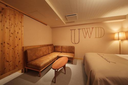 札幌市にあるUNWIND HOTEL & BAR 札幌のベッド、ソファ、椅子が備わる客室です。
