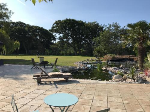 a patio with a table and a bench and a pond at Stay at 'The Elms' in tranquil Church Norton, Selsey - Ground floor bedroom, own private bathroom, quiet beach, 2 acre garden by the sea, on edge of wildlife nature reserve in Selsey