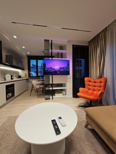 a living room with a white table and an orange chair at Center Apartment Easy_Luxury in Tirana