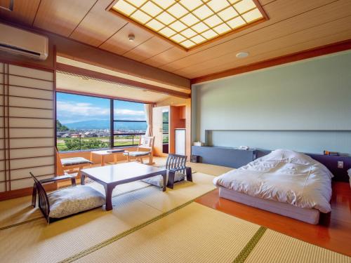 a bedroom with a bed and a table and a window at Fugaku Hanabusa in Izunokuni