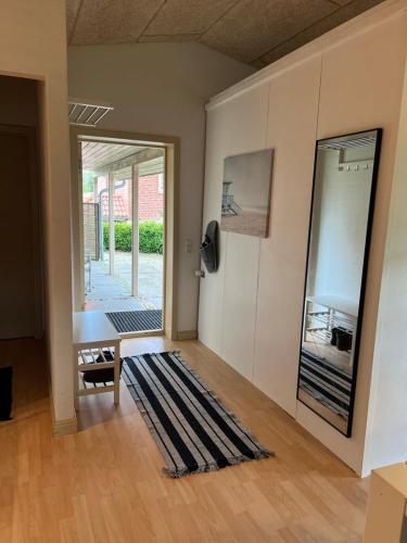 a living room with a door and a rug at Skøn lejlighed til 4 personer in Ansager