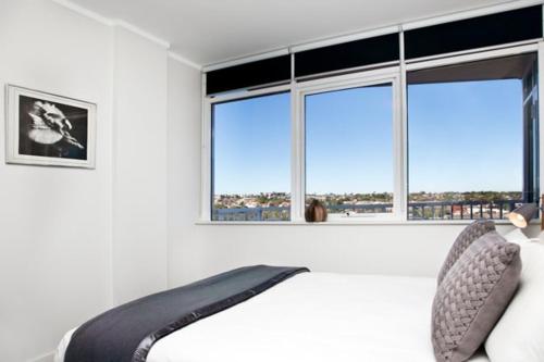 a bedroom with a bed with two pillows and two windows at Seaside Serenity - Stunning Beach Views in Maroubra in Sydney