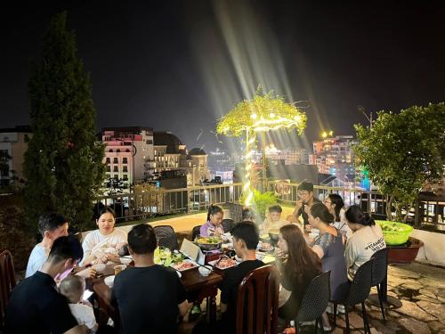 un grupo de personas sentadas en una mesa comiendo comida en WHITE HOUSE - Nhà khách Báo nhân dân en Tam Ðảo