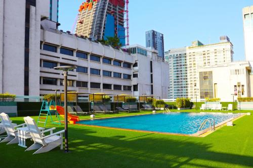 a pool with a slide and chairs and buildings at Evergreen Place Siam by UHG in Bangkok
