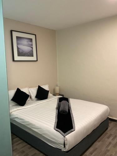 a bedroom with a large white bed with black pillows at The Sky Inn in Kuantan