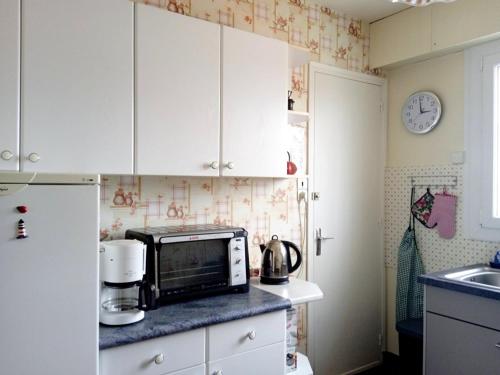 une cuisine avec des placards blancs et un four micro-ondes sur un comptoir dans l'établissement Les pieds dans l'eau, à Saint-Hilaire-de-Riez