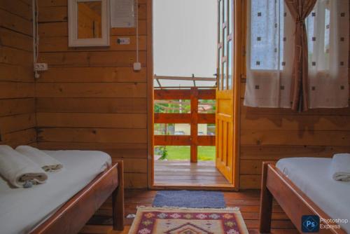 a room with two beds and a door to a porch at Căsuțele dintre vii in Runcu
