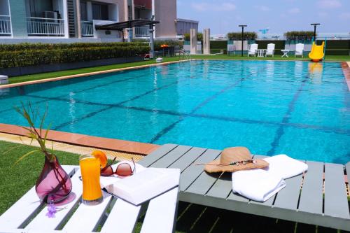 Evergreen Place Siam by UHG في بانكوك: مسبح عليه قبعة و نظارة شمسية على طاولة