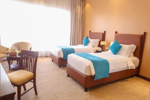 a hotel room with two beds and a window at Happy Days Hotel in Manama