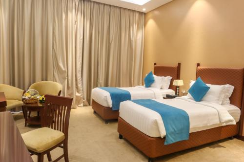 a hotel room with two beds and a table and chairs at Happy Days Hotel in Manama